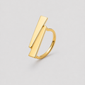 A gold geometric ring featuring two parallel rectangular bar elements set into a smooth band, photographed on a neutral light gray background.