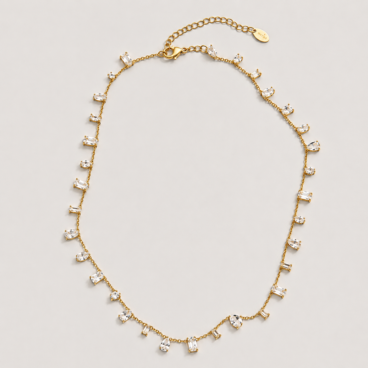 A gold-toned statement necklace featuring multiple clear rectangular-cut crystals set in a dangle design, displayed on a light gray background.