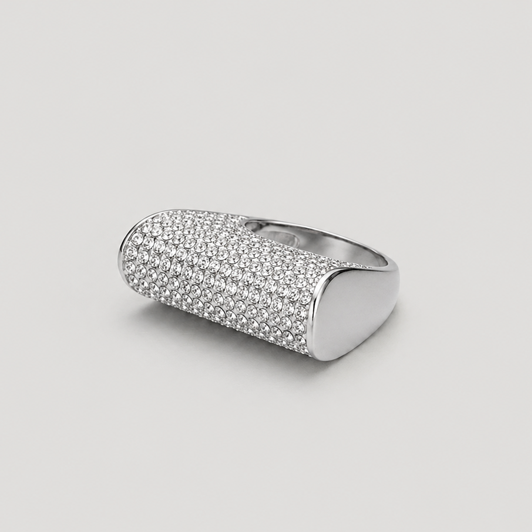 A silver-toned signet ring with a textured, pavé-set oval face, photographed on a neutral light gray background.
