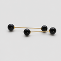 A pair of gold-toned double-bar earrings with four black spherical beads, arranged diagonally on a light gray background.