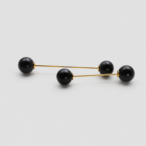 A pair of gold-toned double-bar earrings with four black spherical beads, arranged diagonally on a light gray background.
