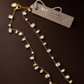 A gold-tone double-strand necklace with clear rhinestone and crystal drops, displayed on a dark brown background with a brand tag that reads 'MARIARICHA'.