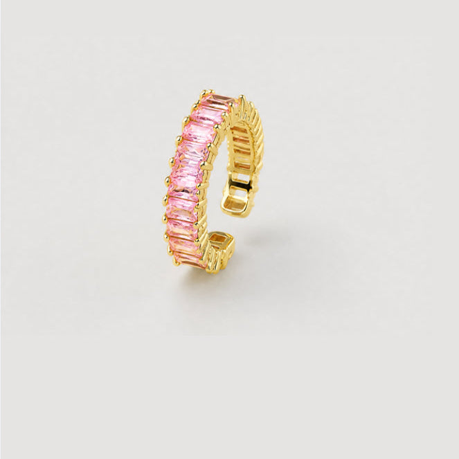 A gold-plated adjustable ring featuring a row of rectangular pink gemstones, set against a plain light gray background.