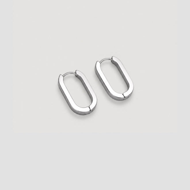 A pair of polished silver oval hoop earrings on a light gray background.