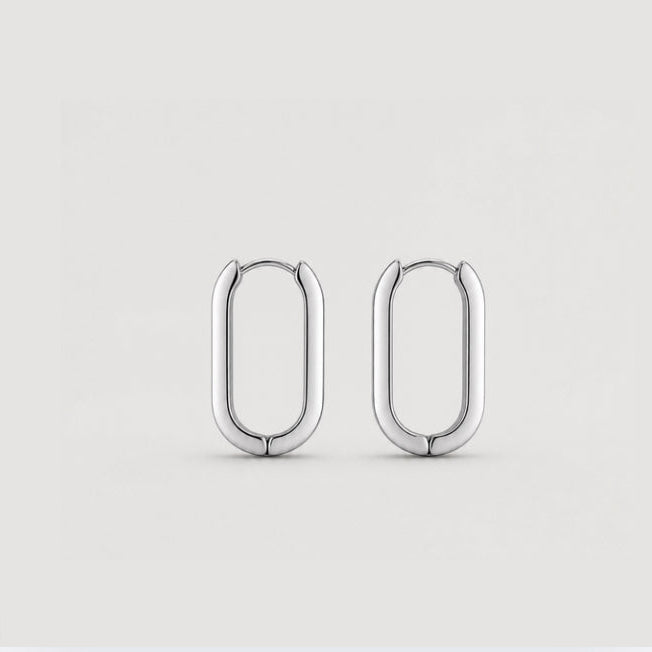 A pair of polished silver hoop earrings with a rounded, elongated oval shape, displayed on a clean light gray background.