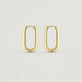 A pair of gold-toned hoop earrings with a rounded, elongated oval shape, displayed on a clean, light gray background.