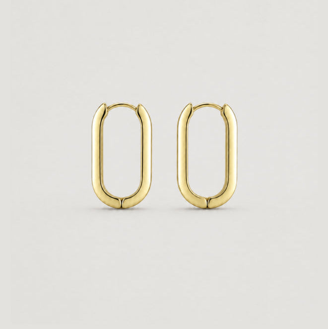 A pair of gold-toned hoop earrings with a rounded, elongated oval shape, displayed on a clean, light gray background.