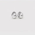 A pair of polished silver stud earrings with a rounded, organic teardrop shape, shown on a plain light gray background.