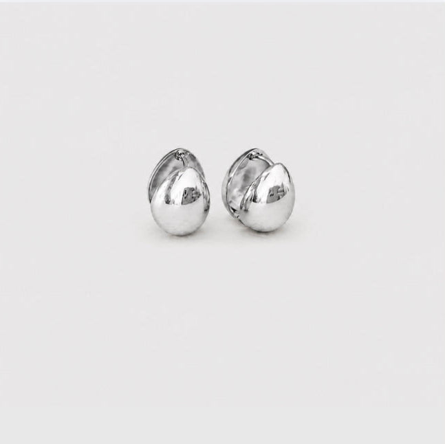 A pair of polished silver stud earrings with a rounded, organic teardrop shape, shown on a plain light gray background.