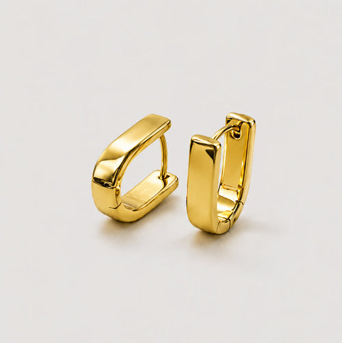 A pair of polished gold huggie hoop earrings with a modern, slightly angled rectangular design, displayed on a clean light gray background.