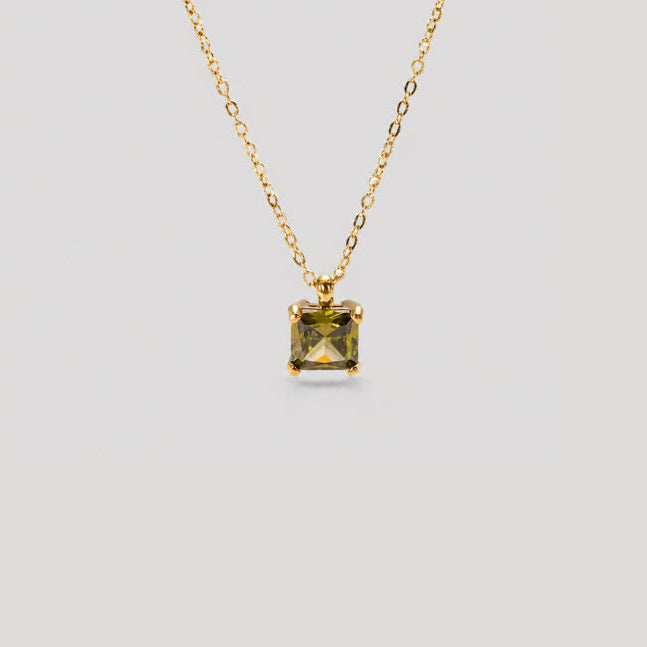 A gold chain necklace with a square-cut olive green gemstone pendant, displayed against a solid light gray background.