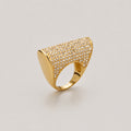 A gold ring with a wide, curved pavé-set top and a smooth polished band, photographed on a light gray background.