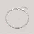 A silver snake chain bracelet with a lobster clasp and extension chain, displayed on a light beige background.