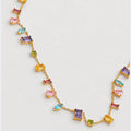 A gold chain necklace featuring multiple small rectangular and marquise-cut gemstones in pink, purple, blue, yellow, and green, arranged symmetrically on a light gray background.